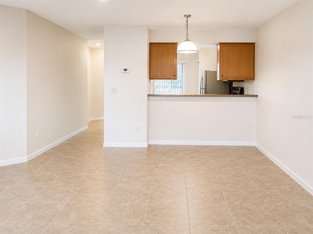 A dining area with tile flooring features a breakfast bar opening to a kitchen — 172 RESERVE CIRCLE UNIT 100, OVIEDO, FL