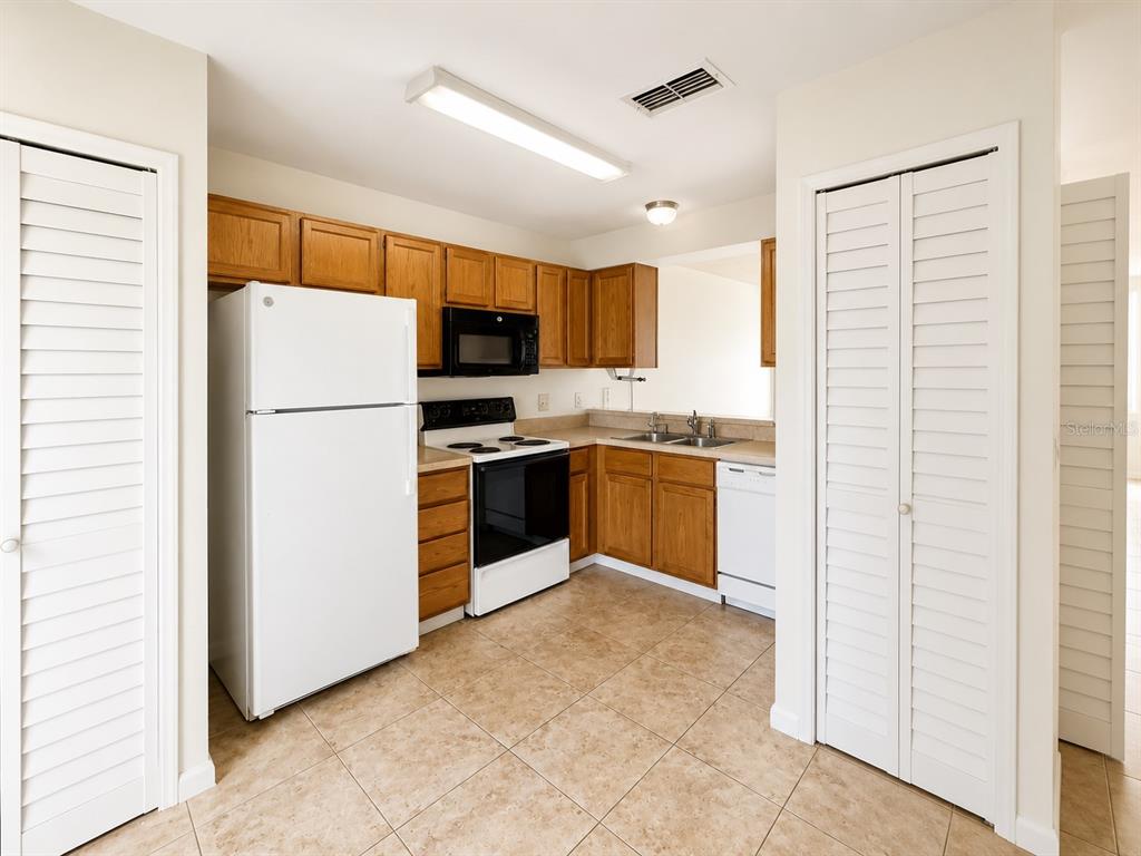 A kitchen with wood cabinets, white appliances, and tile flooring — 172 RESERVE CIRCLE UNIT 100, OVIEDO, FL