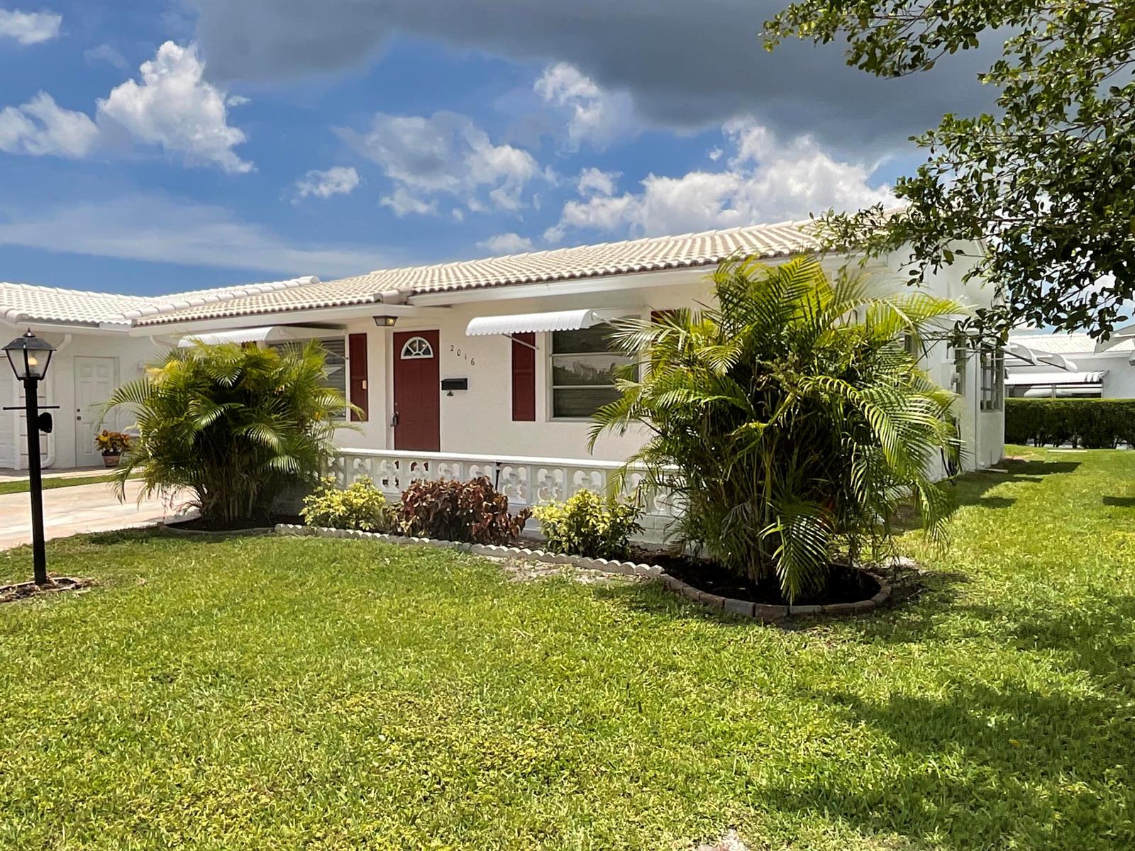 A single-story white house with a red door, palm trees, and a decorative concrete railing — 2016 SW 16th Avenue, Boynton Beach FL 33426, BOYNTON BEACH, FL