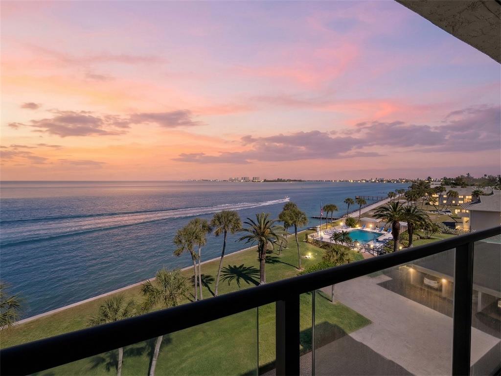 A balcony view overlooking a grassy lawn, palm trees, a swimming pool, and the ocean — 4712 OCEAN BOULEVARD UNIT W10, SARASOTA, FL