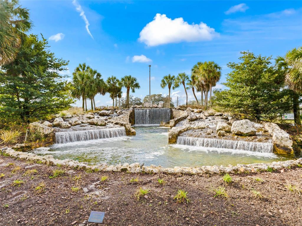 A tiered stone waterfall flows into a small pond surrounded by palm trees and landscaping — TBD SW 148 PL. RD, OCALA, FL