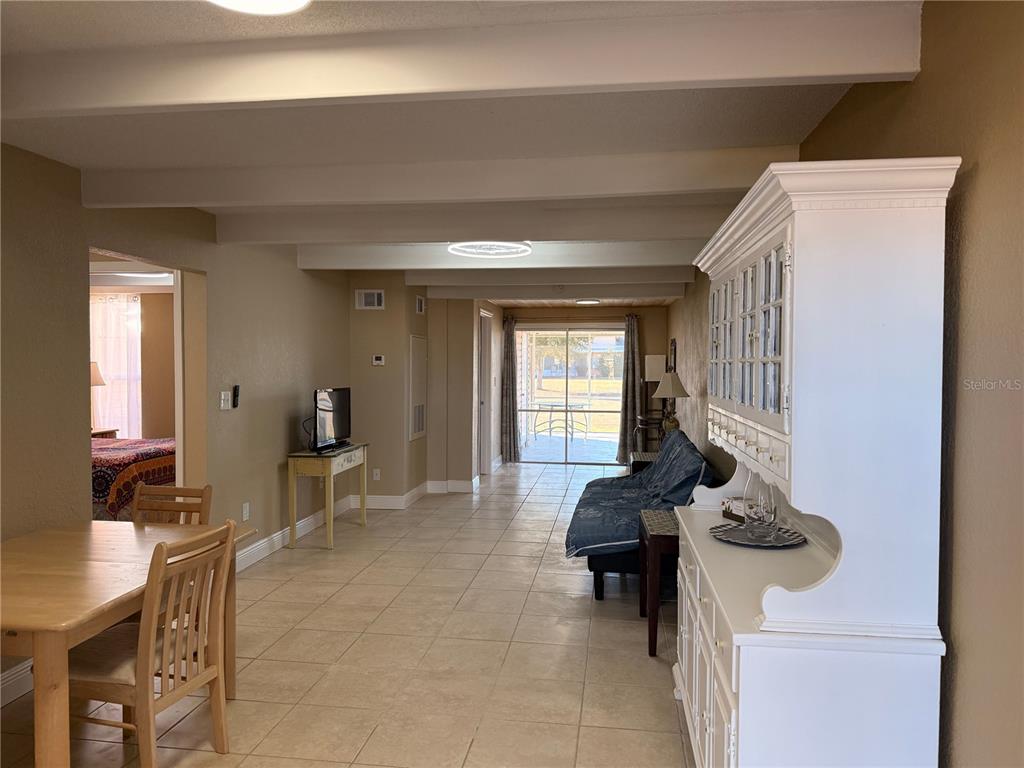 A living and dining area with tile floors, exposed ceiling beams, and a white hutch — 1605 CLUB CIRCLE UNIT 1605, LAKESHORE, FL