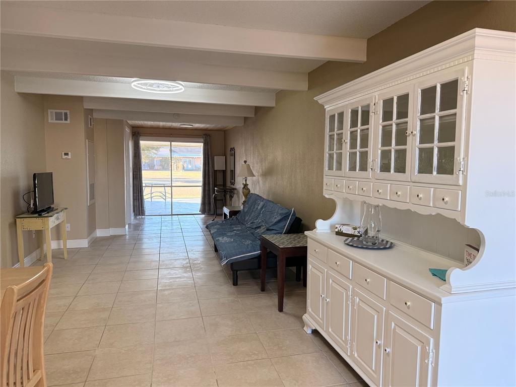 A living room features tile floors, a white hutch, a blue sofa, and sliding glass doors — 1605 CLUB CIRCLE UNIT 1605, LAKESHORE, FL
