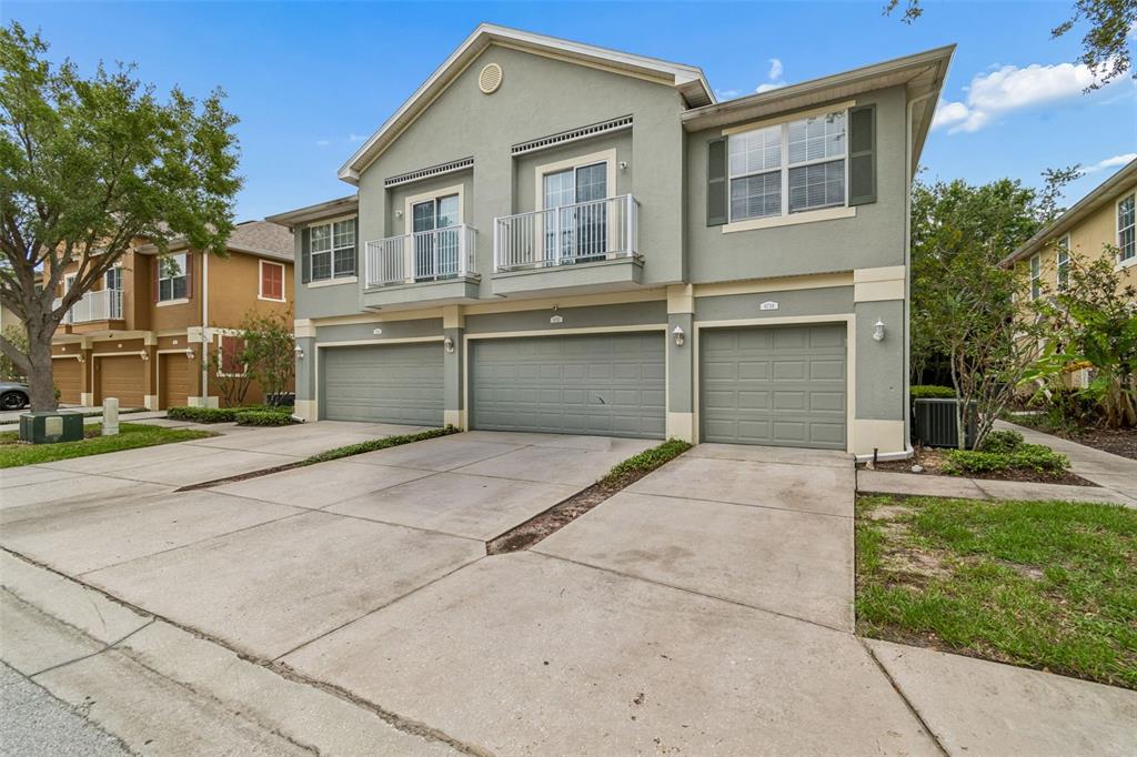 A two-story townhouse exterior with three garage doors and two upper-level balconies — 6734 BREEZY PALM DRIVE, RIVERVIEW, FL