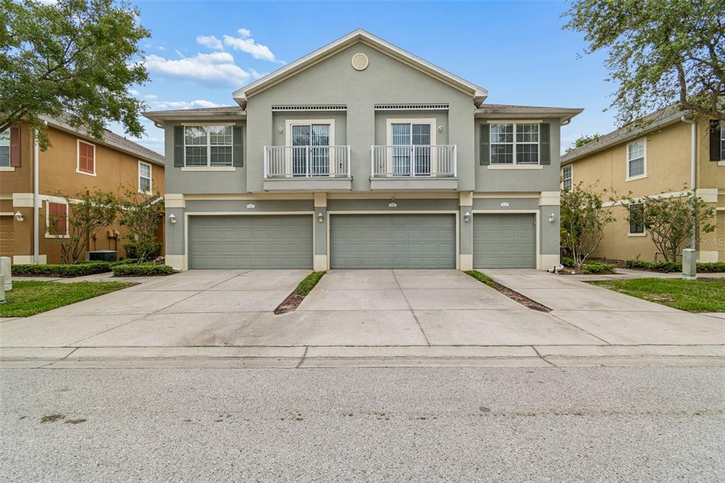 A two-story residential building features three garage doors and two upper-level balconies — 6734 BREEZY PALM DRIVE, RIVERVIEW, FL
