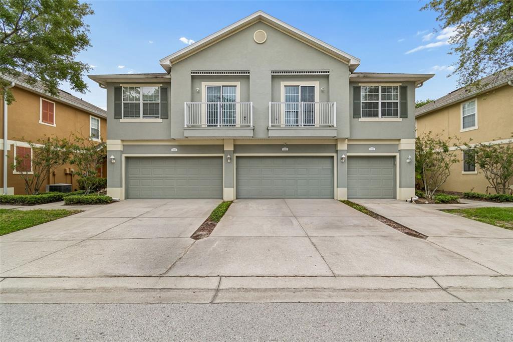 A two-story townhouse exterior features three garage doors and two upper-level balconies — 6734 BREEZY PALM DRIVE, RIVERVIEW, FL