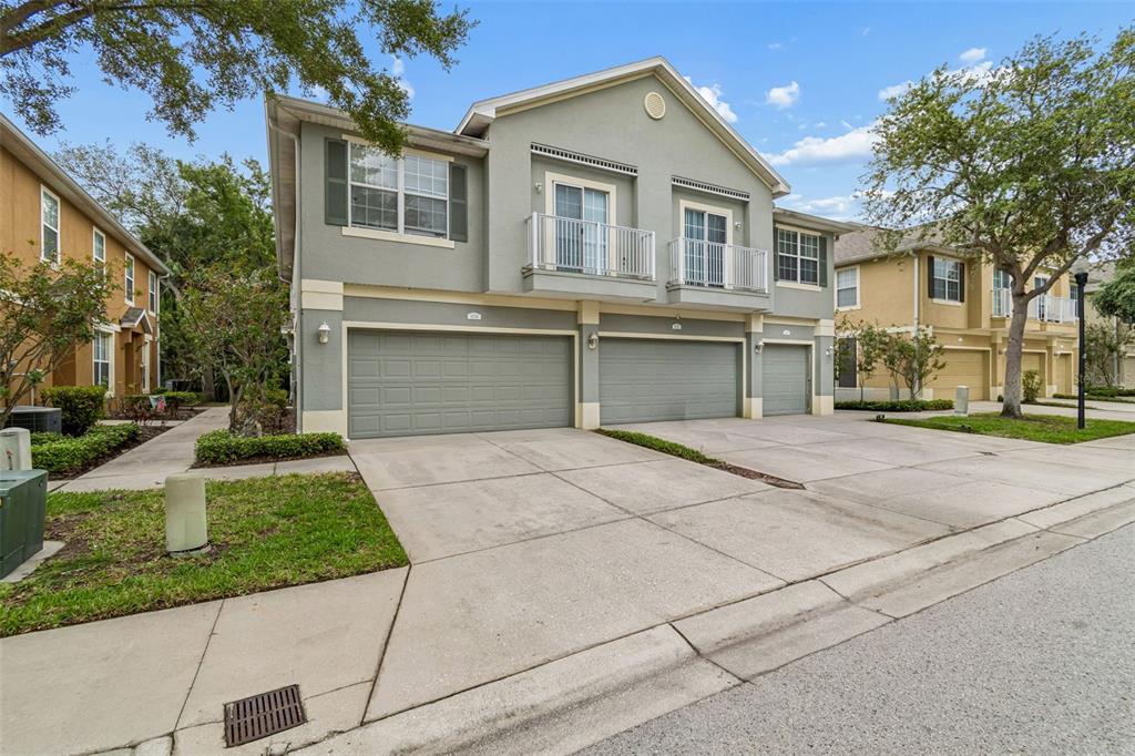 A three-story townhouse exterior with three garage doors and two upper-level balconies — 6734 BREEZY PALM DRIVE, RIVERVIEW, FL