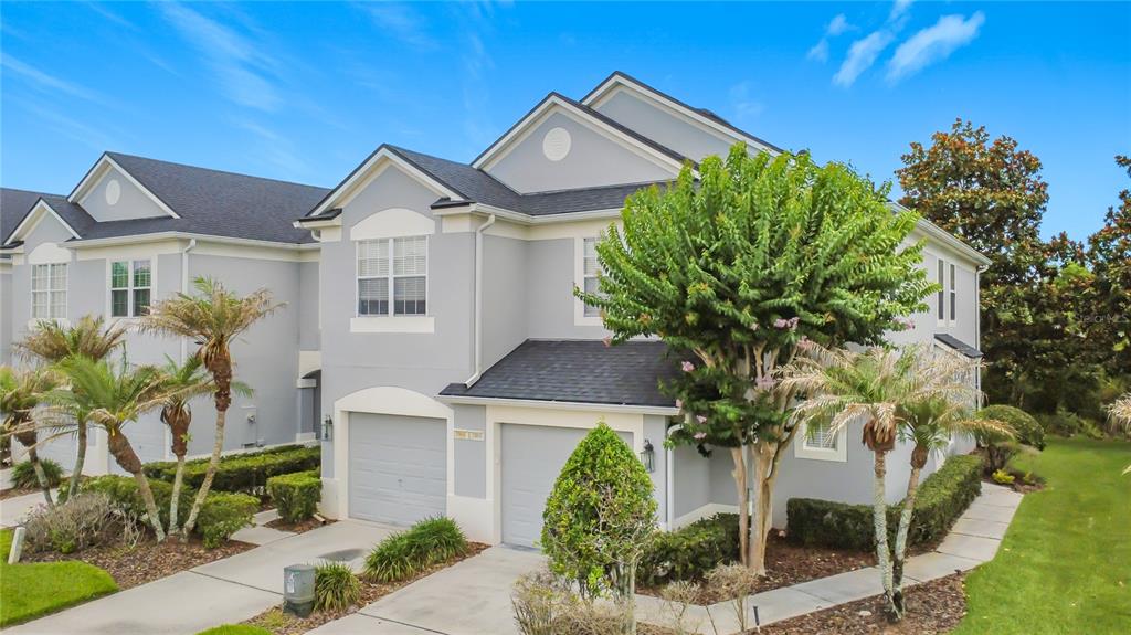 A two-story gray townhouse with two garage doors, a shingled roof, and landscaped front yard — 1060 ROCK HARBOR AVENUE, ORLANDO, FL
