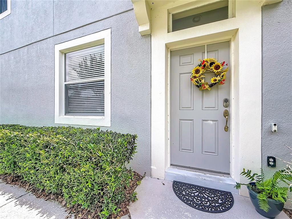 A gray front door with a sunflower wreath sits next to a window and hedge — 1060 ROCK HARBOR AVENUE, ORLANDO, FL