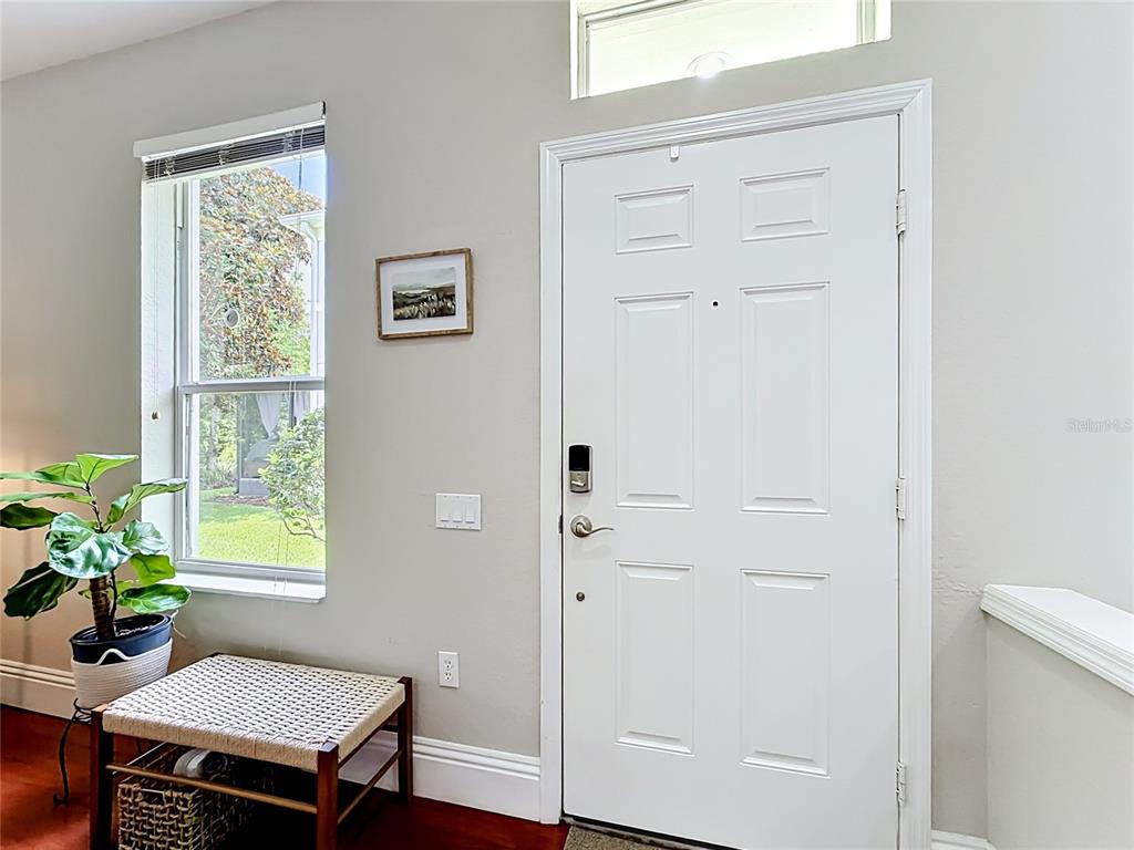 A white front door with a smart lock sits beside a window and bench — 1060 ROCK HARBOR AVENUE, ORLANDO, FL