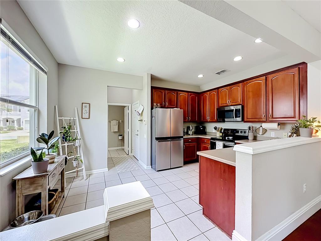 A kitchen features wood cabinets, stainless steel appliances, and tile flooring — 1060 ROCK HARBOR AVENUE, ORLANDO, FL