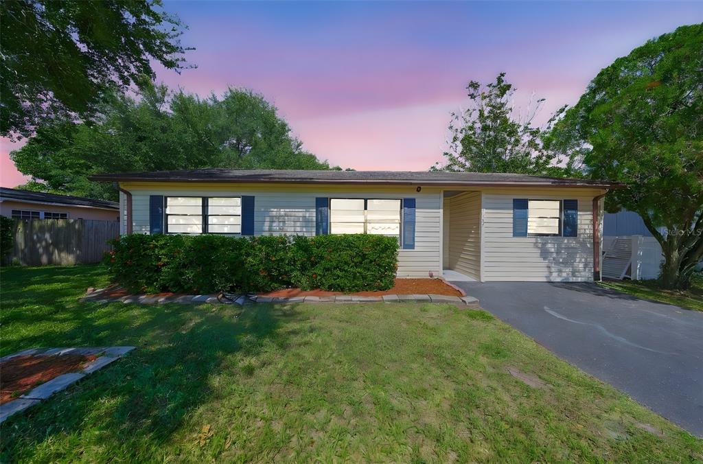 A single-story house with light siding, blue shutters, a front lawn, and a driveway — 1507 76TH AVENUE N, ST PETERSBURG, FL
