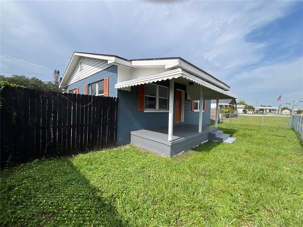 A blue house with a covered porch and a black wooden fence in the yard — 1206 E CANAL STREET, MULBERRY, FL