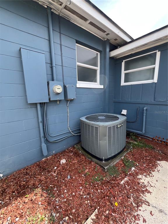 An exterior view of a blue house showing an HVAC unit, electrical meter, and windows — 1206 E CANAL STREET, MULBERRY, FL