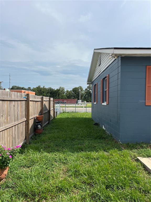 A side view of a blue house with orange shutters next to a wooden fence — 1206 E CANAL STREET, MULBERRY, FL