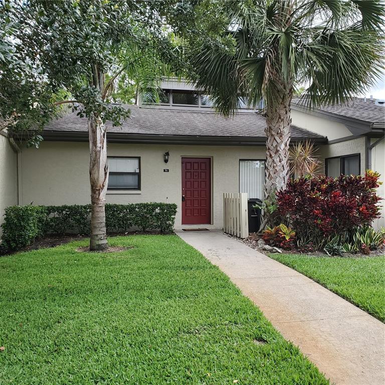 A single-story home with a red front door, a concrete walkway, and palm trees — 70 JOANNE PLACE UNIT 70, OLDSMAR, FL