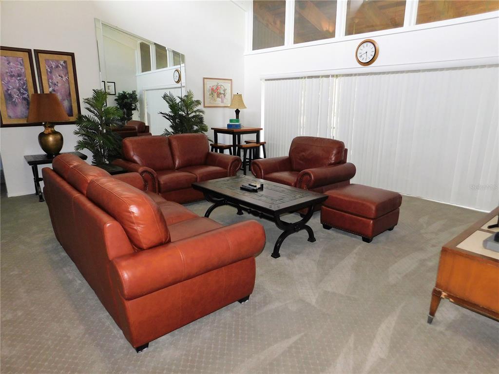 A living room features brown leather furniture, a coffee table, and a large wall mirror — 70 JOANNE PLACE UNIT 70, OLDSMAR, FL