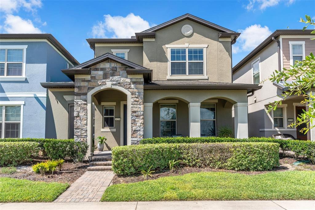 A two-story house with a stone-accented entryway, arched porch, and a manicured hedge — 14230 MURCOTT BLOSSOM BOULEVARD, WINTER GARDEN, FL