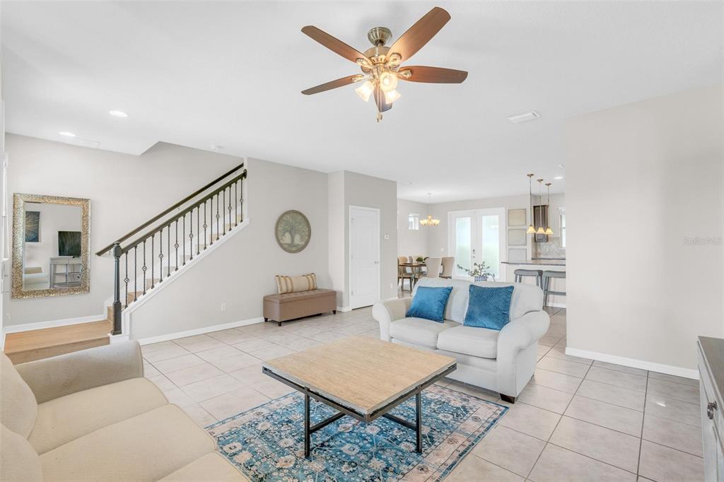 A living room features tile flooring, a staircase with a railing, and a ceiling fan — 14230 MURCOTT BLOSSOM BOULEVARD, WINTER GARDEN, FL