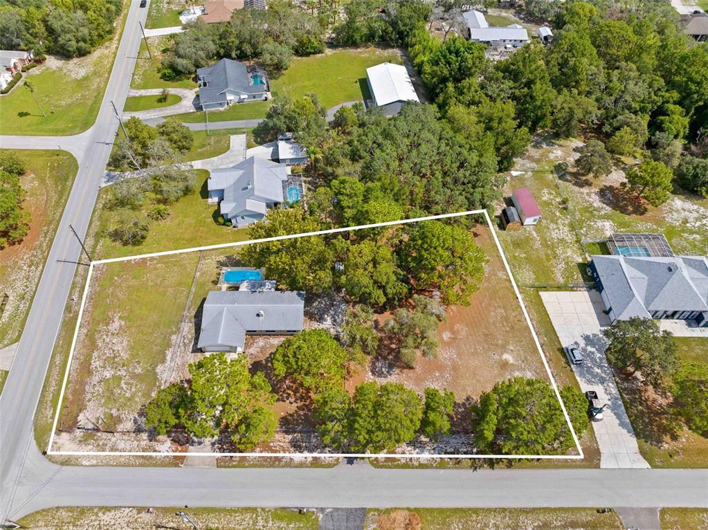 An aerial view shows a residential property with a house, pool, and large wooded yard — 16517 DIPLOMAT DRIVE, SPRING HILL, FL