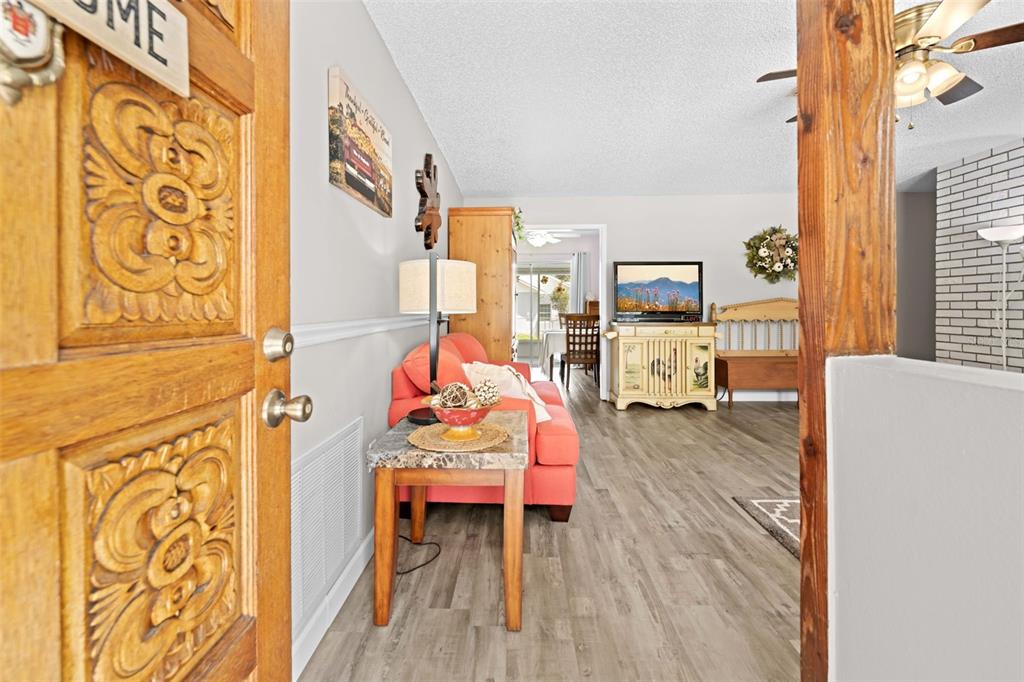 A view from a doorway into a living room with wood-look flooring and orange sofa — 16517 DIPLOMAT DRIVE, SPRING HILL, FL