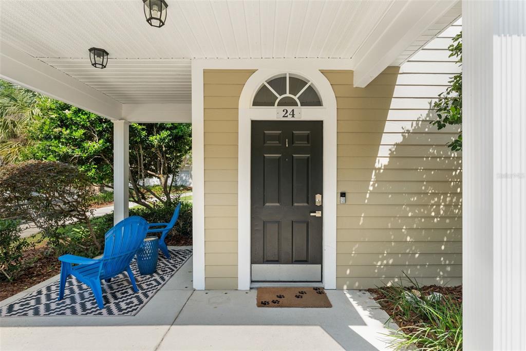 A covered front porch features a dark door with a transom window and blue chairs — 10000 SW 52ND AVENUE UNIT 24, GAINESVILLE, FL