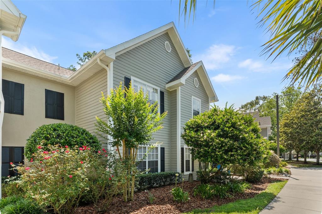 A two-story house with light green siding, black shutters, and a landscaped front yard — 10000 SW 52ND AVENUE UNIT 24, GAINESVILLE, FL