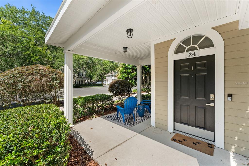 A covered front porch features a black door, blue chairs, and a patterned rug — 10000 SW 52ND AVENUE UNIT 24, GAINESVILLE, FL