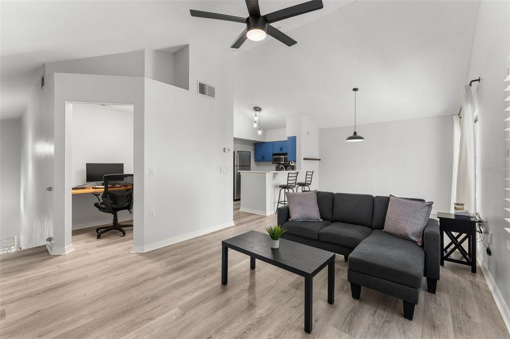 A living room with light wood floors, a gray sectional sofa, and an adjacent office nook — 10000 SW 52ND AVENUE UNIT 24, GAINESVILLE, FL