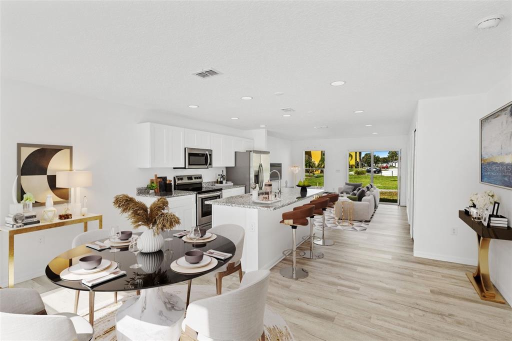 This open-concept kitchen and dining area features white cabinetry, granite countertops, and light wood flooring — 172 BOWIE LANE UNIT B, KISSIMMEE, FL