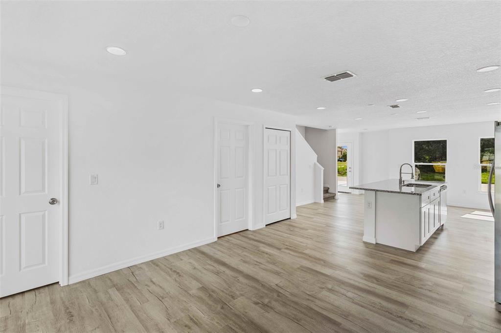 A bright, open-concept kitchen and living area featuring white walls, light wood flooring, and cabinetry — 172 BOWIE LANE UNIT B, KISSIMMEE, FL