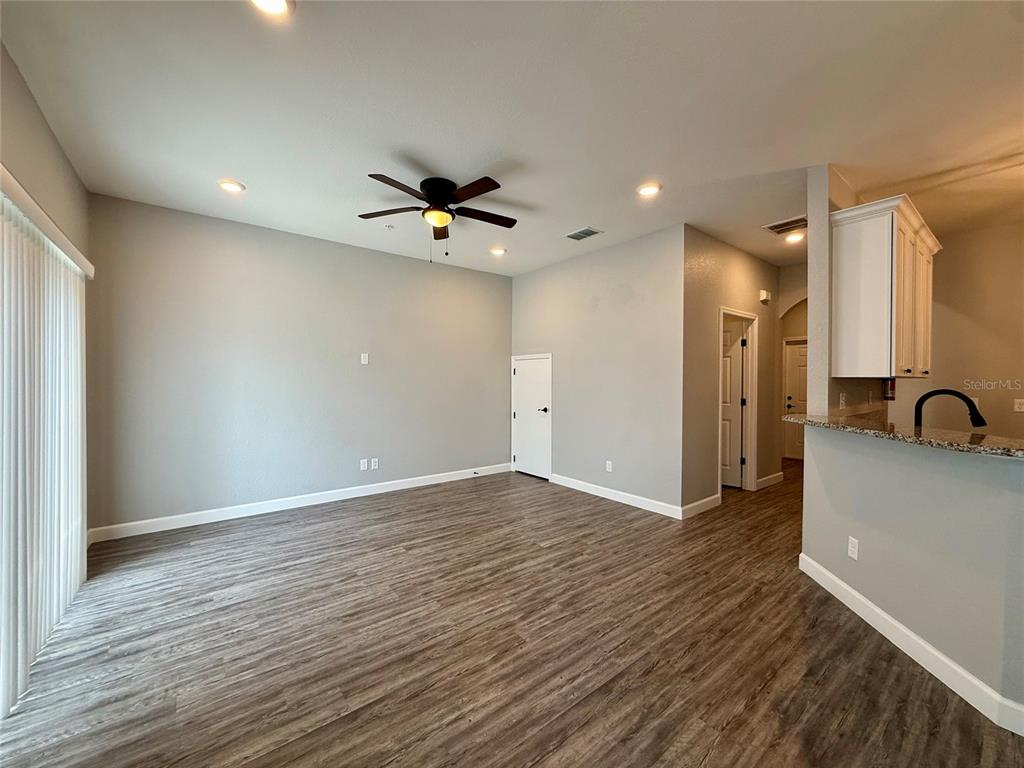 A living room with a blue rug, gray sofa, two armchairs, and a wall-mounted television — 2604 TANOAK TERRACE, WINTER HAVEN, FL