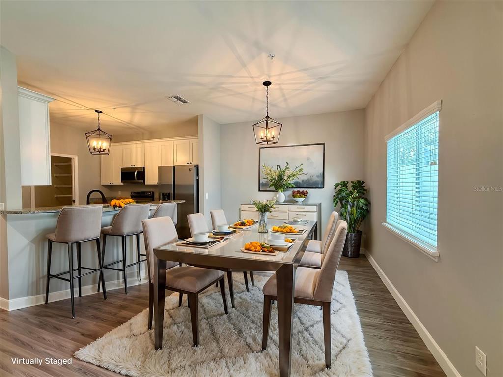 An open-concept living room features wood-look flooring, a ceiling fan, and a kitchen breakfast bar — 2604 TANOAK TERRACE, WINTER HAVEN, FL