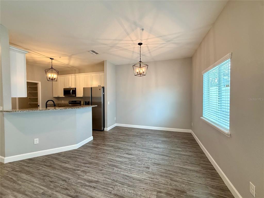 A dining area with a table and chairs sits adjacent to a kitchen with stools — 2604 TANOAK TERRACE, WINTER HAVEN, FL