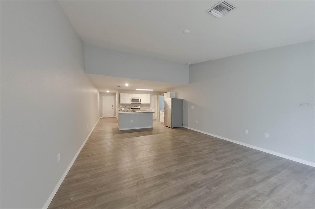An open-concept living area features light gray walls, wood-look flooring, and a small kitchen island — 9135 AEGEAN CIRCLE, LEHIGH ACRES, FL