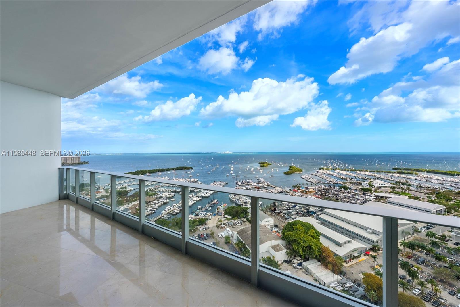 A high-rise balcony with glass railings overlooks a marina and the ocean — 2627 S Bayshore Dr # 2904, Miami FL 33133, MIAMI, FL