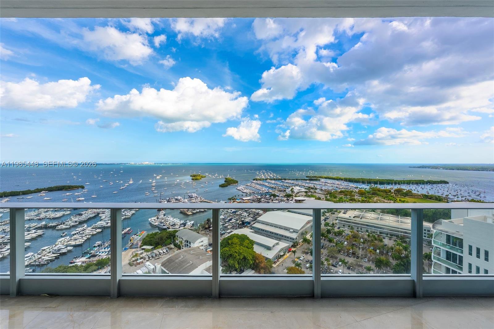 A high-rise balcony overlooks a marina, a large parking lot, and the open ocean — 2627 S Bayshore Dr # 2904, Miami FL 33133, MIAMI, FL