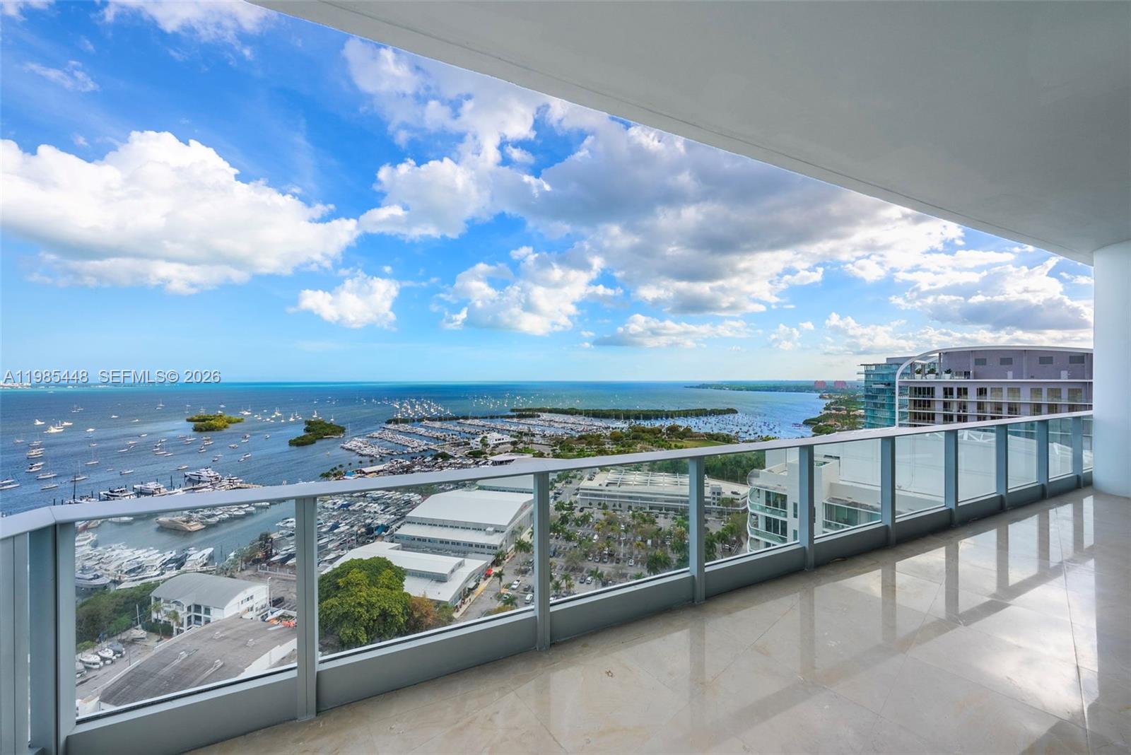 A high-rise balcony with a glass railing overlooks a marina and the ocean — 2627 S Bayshore Dr # 2904, Miami FL 33133, MIAMI, FL