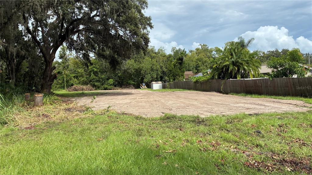 A cleared, level dirt lot is bordered by a wooden fence and mature trees — 0 EAST CHERRY STREET, PLANT CITY, FL