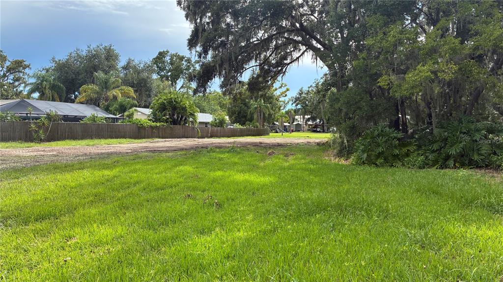 A grassy, vacant lot features a dirt path and mature trees under a cloudy sky — 0 EAST CHERRY STREET, PLANT CITY, FL