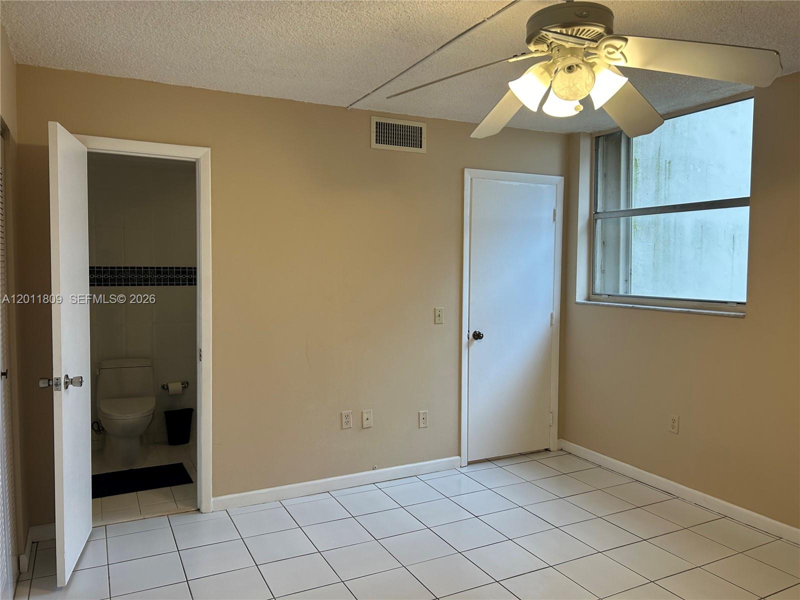 A room with white tile flooring, a ceiling fan, a window, and an open bathroom door — 9411 SW 4th St # 202, Miami FL 33174, MIAMI, FL