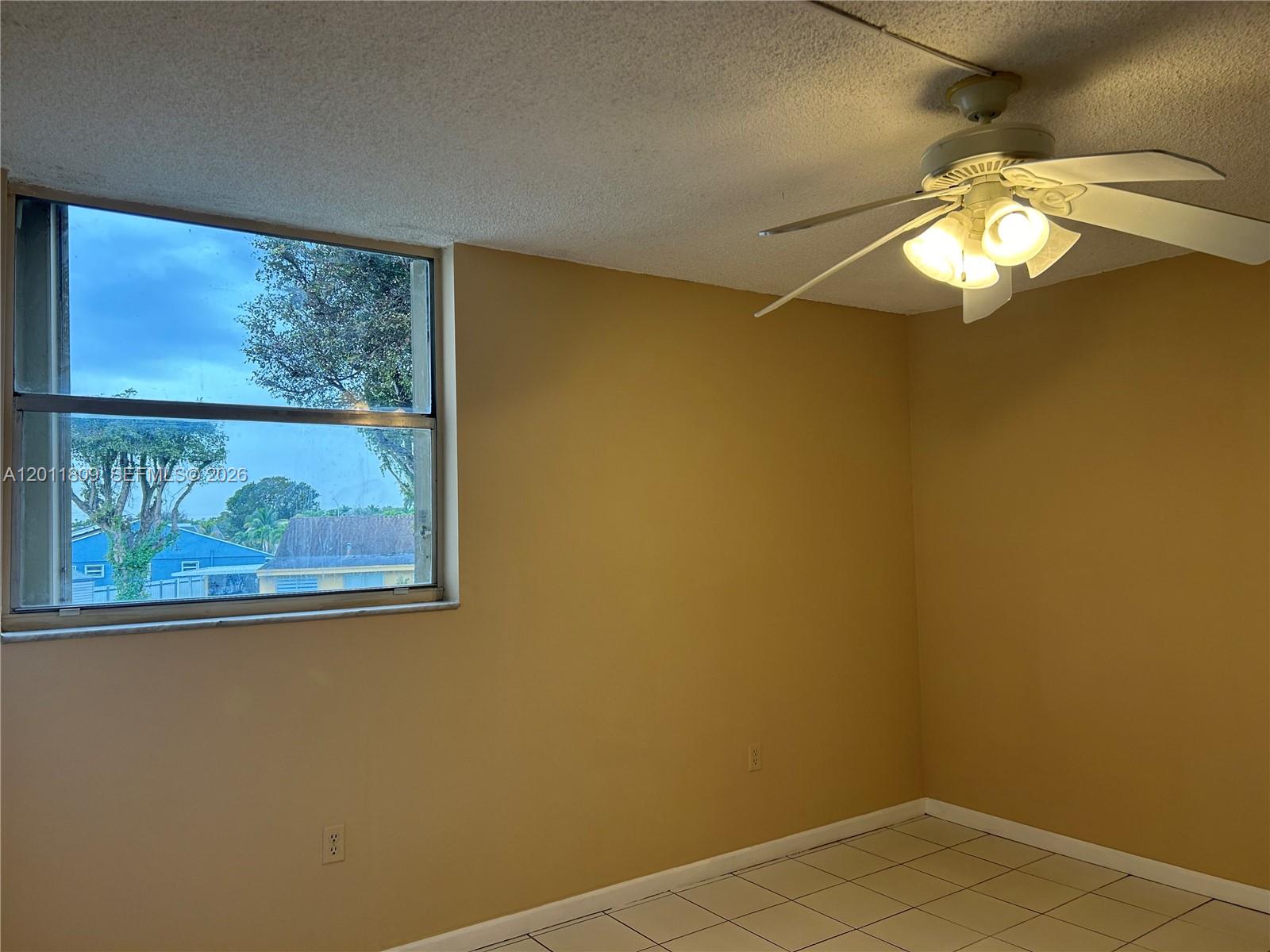 A room with tan walls, white tile flooring, a ceiling fan, and a large window — 9411 SW 4th St # 202, Miami FL 33174, MIAMI, FL