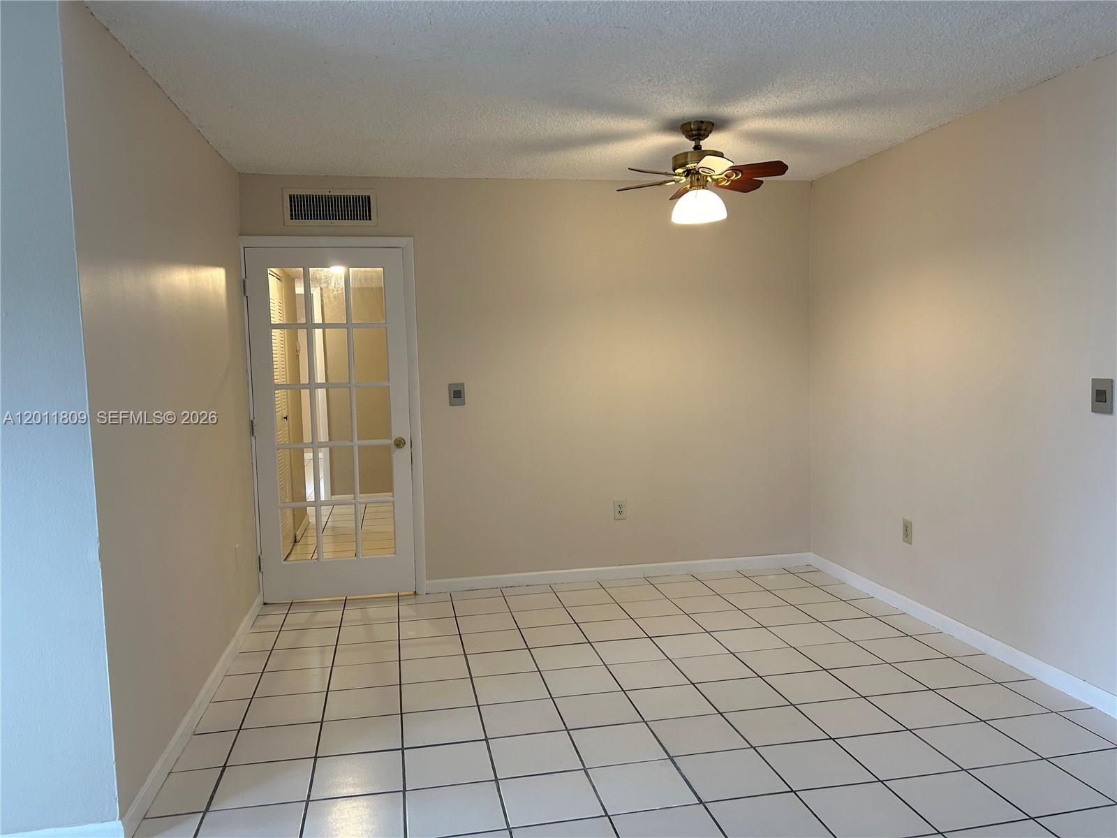An empty room features white tile flooring, beige walls, and a ceiling fan — 9411 SW 4th St # 202, Miami FL 33174, MIAMI, FL