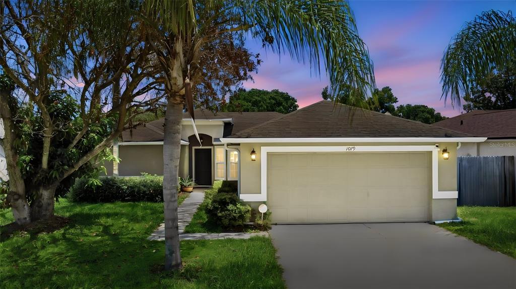 A single-story house with a two-car garage and a palm tree in the front yard — 1079 SUNSHINE WAY SW, WINTER HAVEN, FL