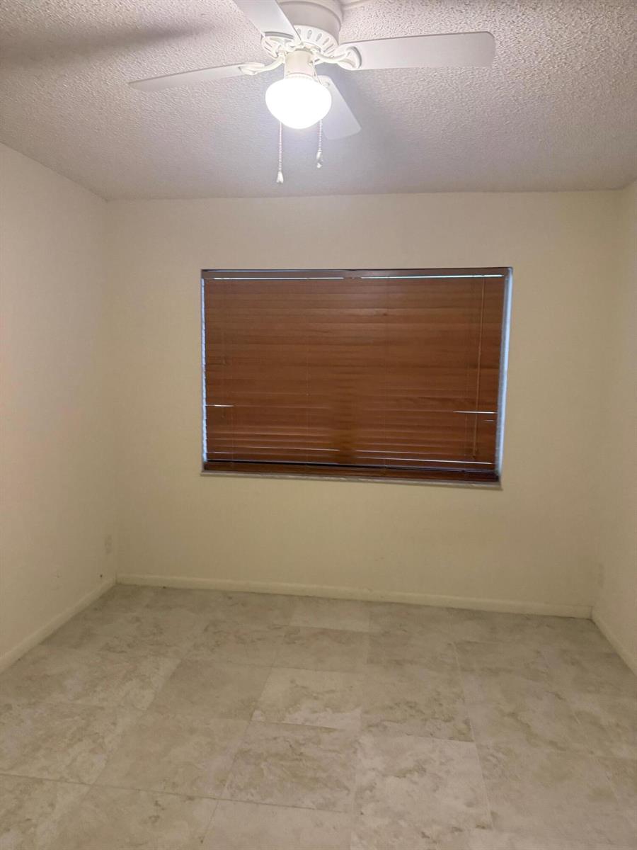 An empty room with light-colored tile flooring, white walls, and a ceiling fan — 4394 NW 9th Avenue # 1a, Pompano Beach FL 33064, POMPANO BEACH, FL