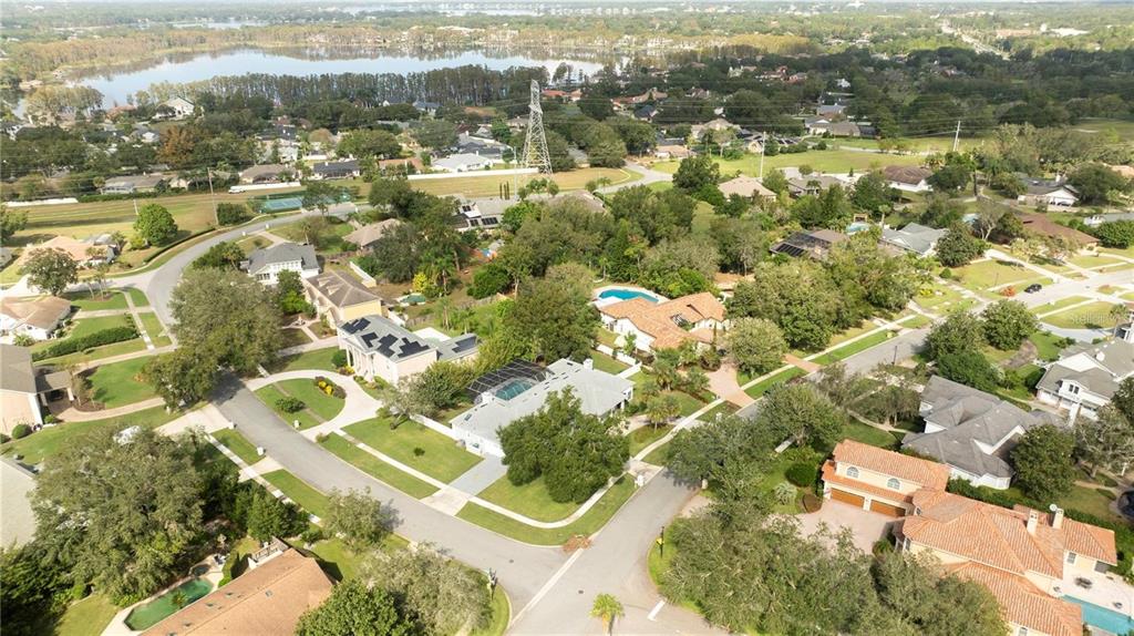 An aerial view shows a suburban neighborhood with houses, swimming pools, and a nearby lake — 5646 MASTERS BOULEVARD, ORLANDO, FL