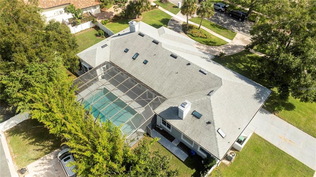 An aerial view shows a house with a gray shingled roof and a screened-in pool — 5646 MASTERS BOULEVARD, ORLANDO, FL