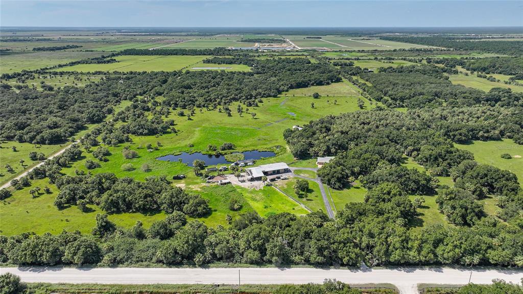 An aerial view shows a rural property with a pond, outbuildings, and surrounding wooded pastures — 43451 & 43631 FARABEE ROAD, PUNTA GORDA, FL