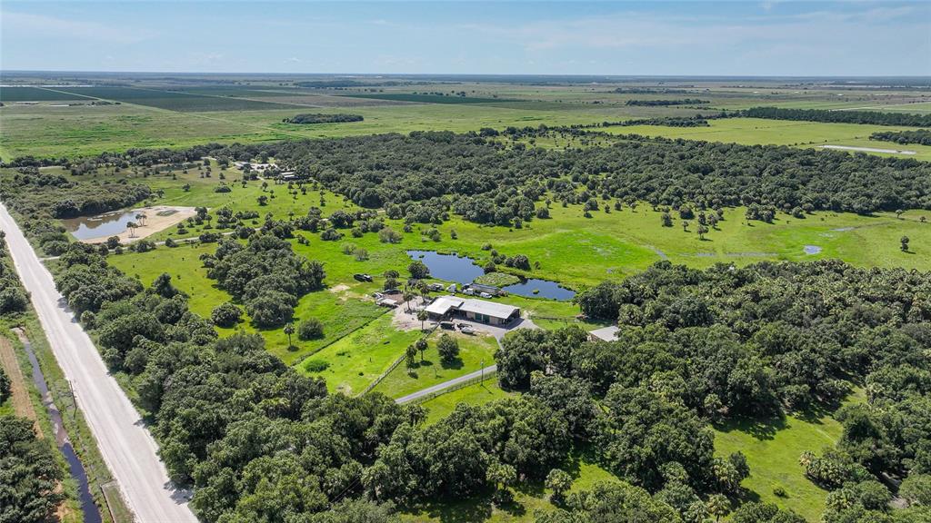 An aerial view of a rural property featuring a large barn, ponds, and wooded acreage — 43451 & 43631 FARABEE ROAD, PUNTA GORDA, FL