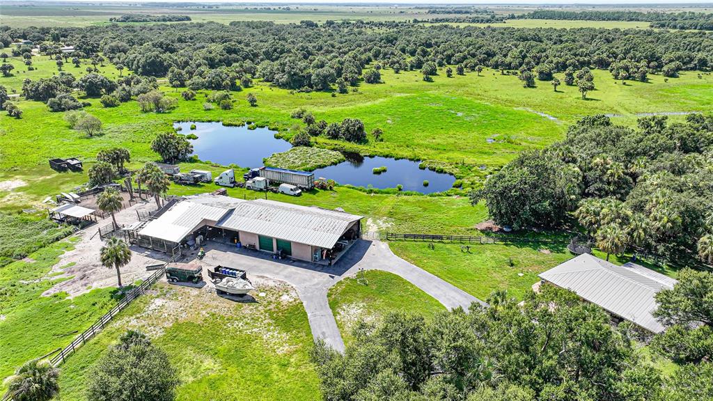 An aerial view shows a rural property with a large metal barn, house, and pond — 43451 & 43631 FARABEE ROAD, PUNTA GORDA, FL